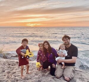 MCF Director of Donor Engagement, Caitlin Ryan, poses with her family on a beach.