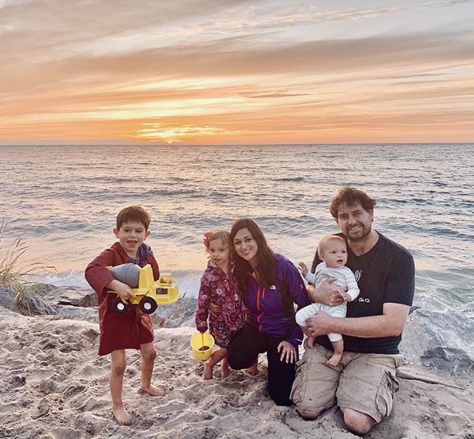 MCF Director of Donor Engagement, Caitlin Ryan, poses with her family on a beach.