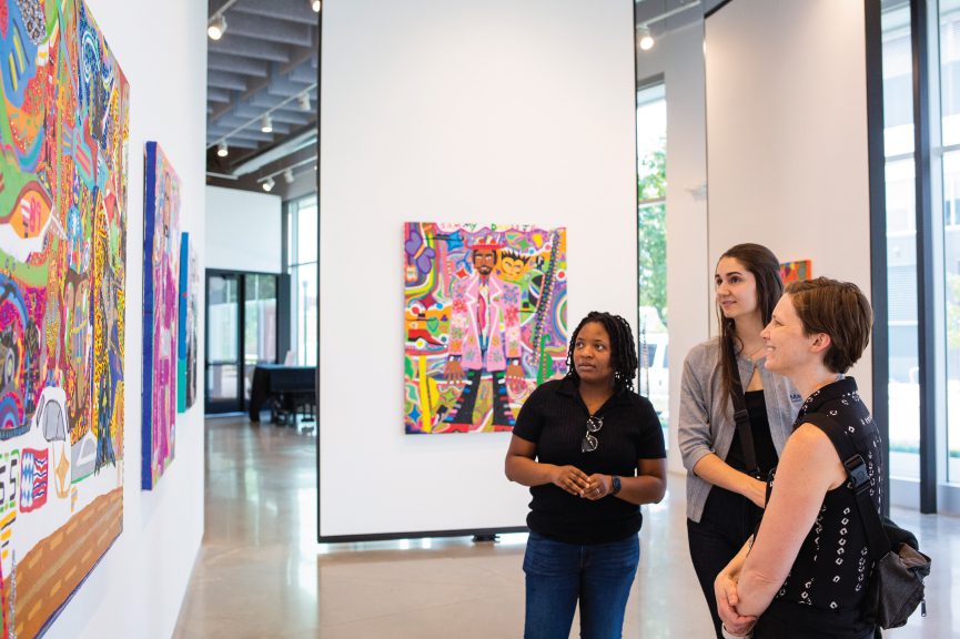 MCF staff member Jazzmine Haygood, Julia Carabelli and Liz Teubert looking at paintings in a gallery at Art + Lit Lab