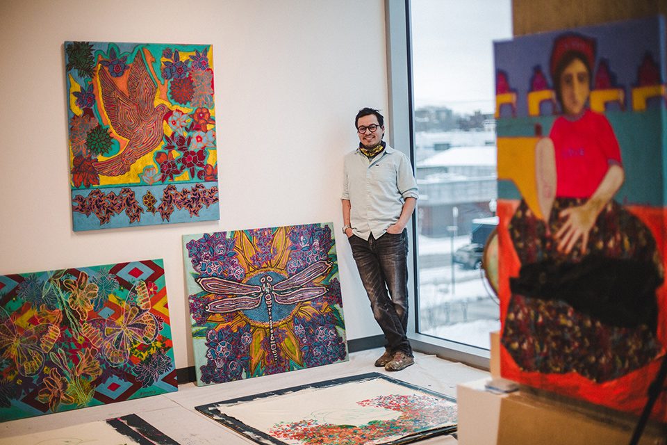 An artist poses with several of his large pieces of art in a studio at Art + Lit Lab along the East Washington art cooridor.