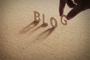 BLOG wood word on compressed board with human's finger at G letter