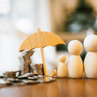 three wooden figures standing under an umbrella next to a stack of coins