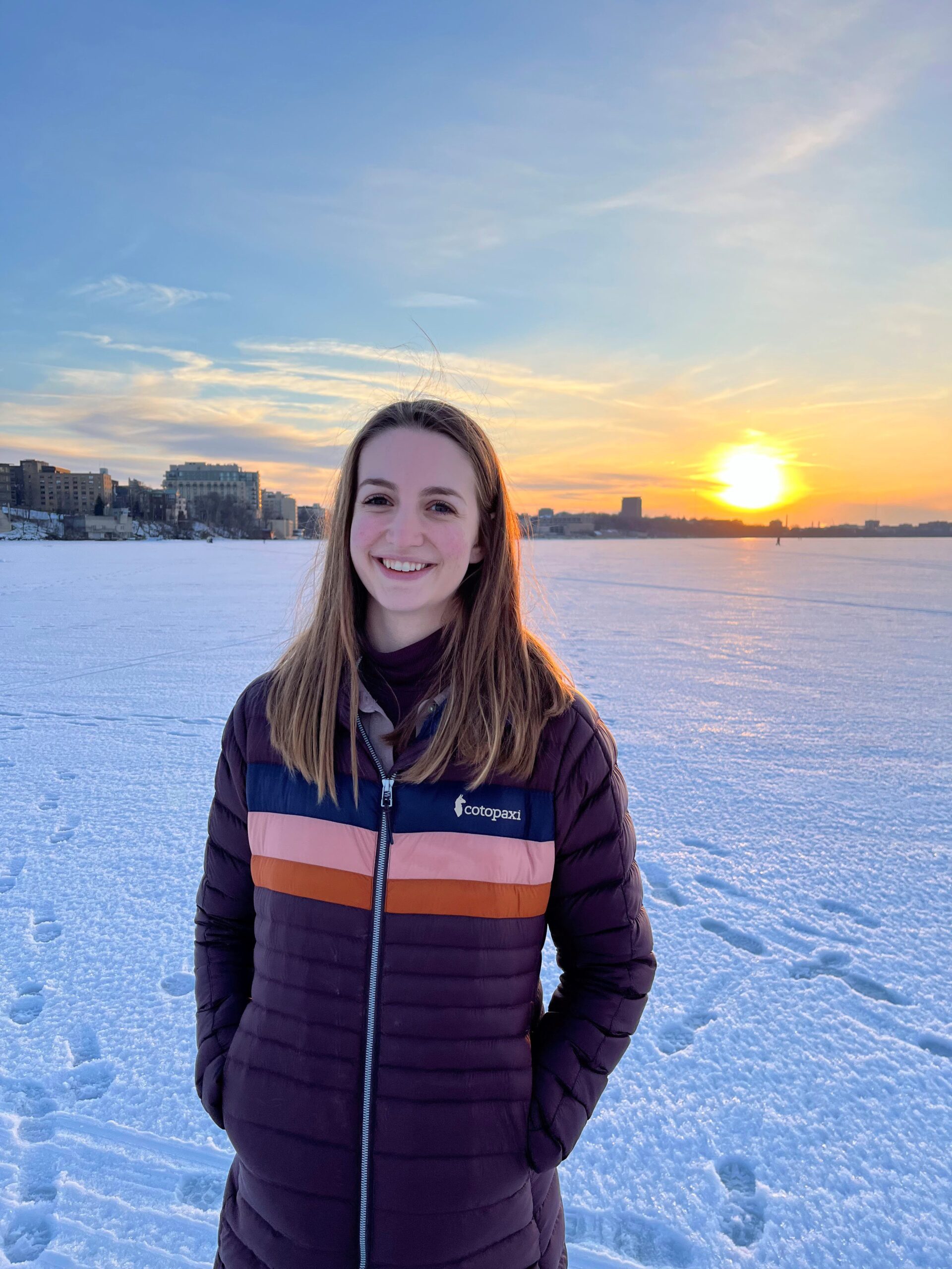 Candid photo of Catherine Frerker at sunset in the winter with the Madison skyline behind her.