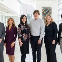 Group photo of MCF's donor engagement team in a large, white room with windows