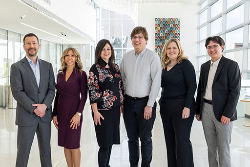 Group photo of MCF's donor engagement team in a large, white room with windows