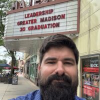Photo of Andy Davey in front of the Majestic Theater in Madison's marquee, which reads Leadership Greater Madison 30 Graduation
