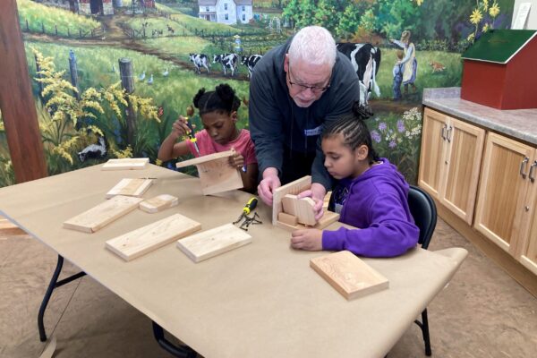 Kids assemble birdhouses with help from an older man