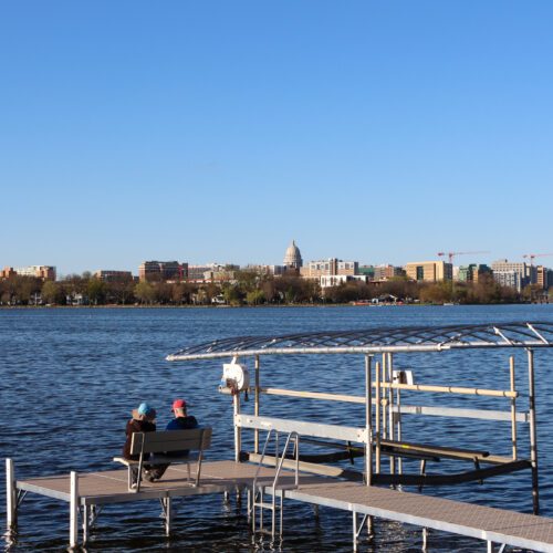 Man and Woman sitting on dock overlooking the Madison skyline