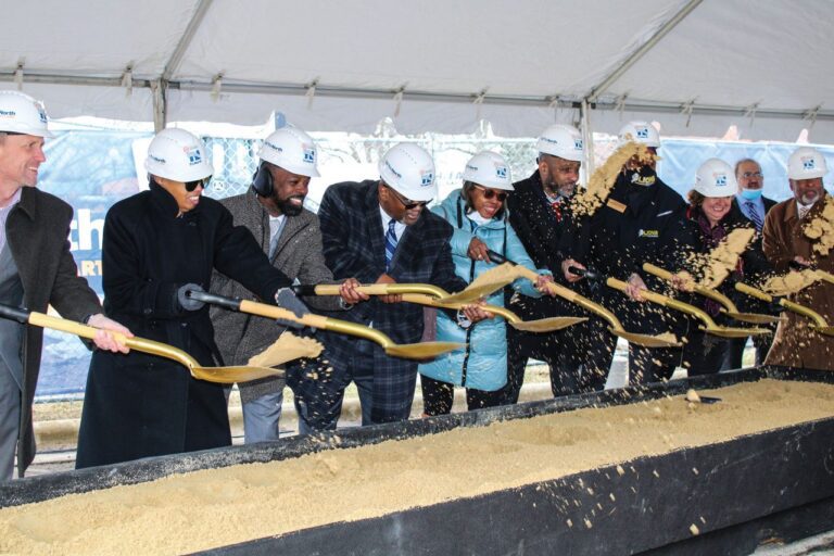 People lifting shovels of dirt up at the same time during a ground breaking ceremony