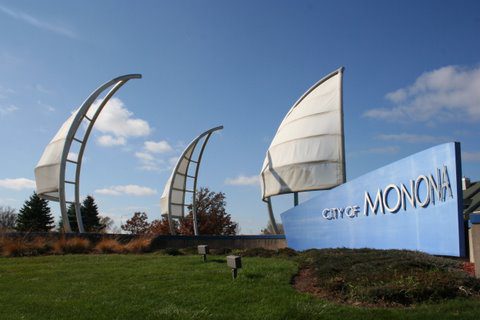 City of Monona blue welcome sign with sails behind it