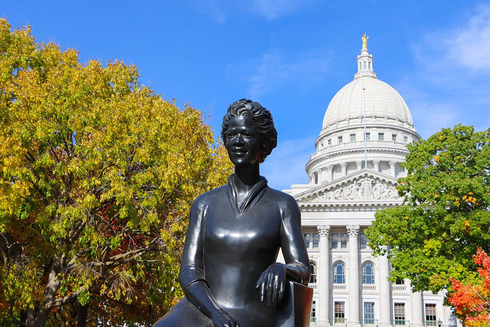 photo looking straight at the statue of Velvalea Phillips, with with Wisconsin State Capitol in the background.