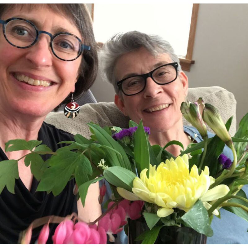 Carin Bringelson and Bev Buhr sitting together with a bouquet of flowers