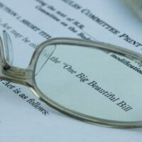 Glasses sitting on a paper that says "One Big Beautiful Bill"