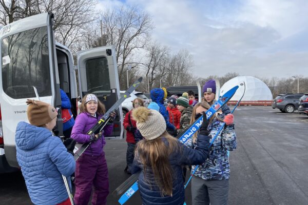 kids unload bus with ski equiptment