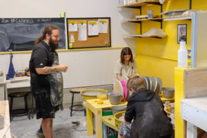 kids and instructor making pottery