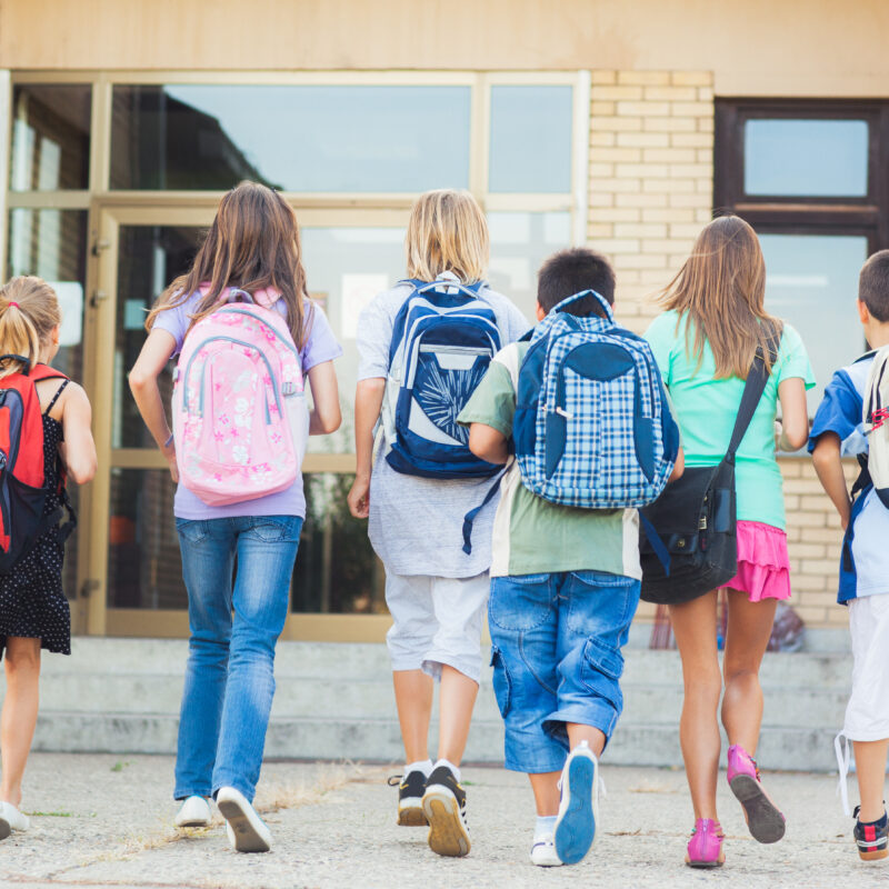 Group of kids running towards the entrance of a school