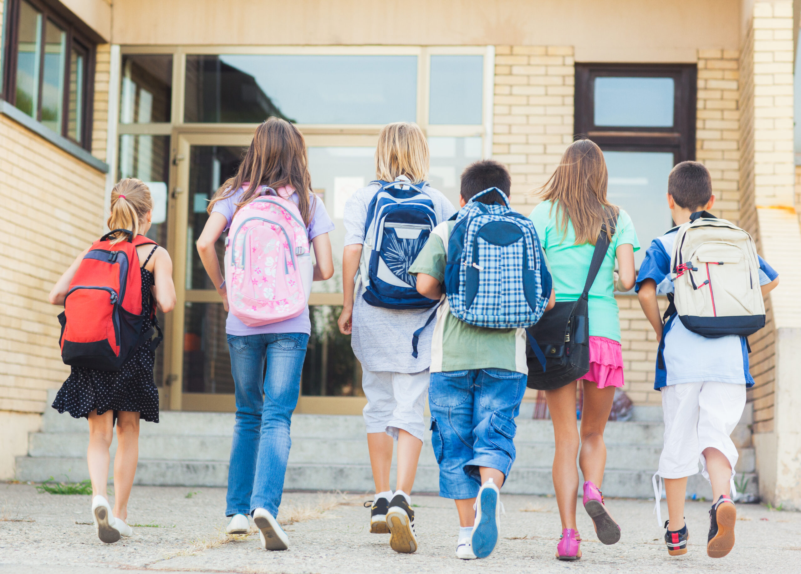 Group of kids running towards the entrance of a school