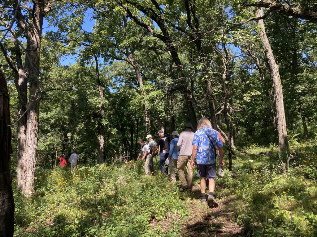 A group of people walk through a forest on a hiking trail