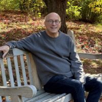 Dan sits on a bench smiling