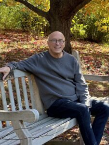 Dan sits on a bench smiling