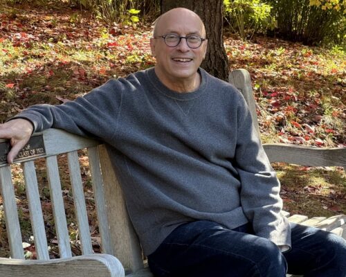Dan sits on a bench smiling